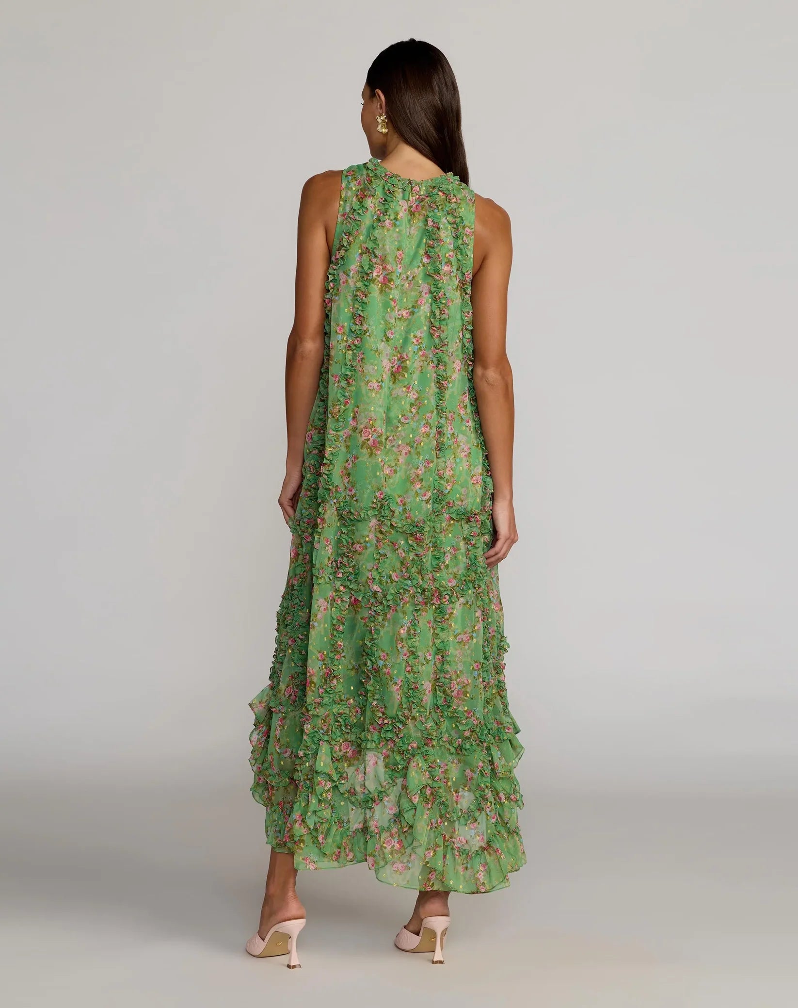 Woman wearing a green floral dress against a plain background