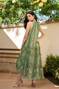 Woman in a green floral dress standing outdoors with trees and a bench in the background