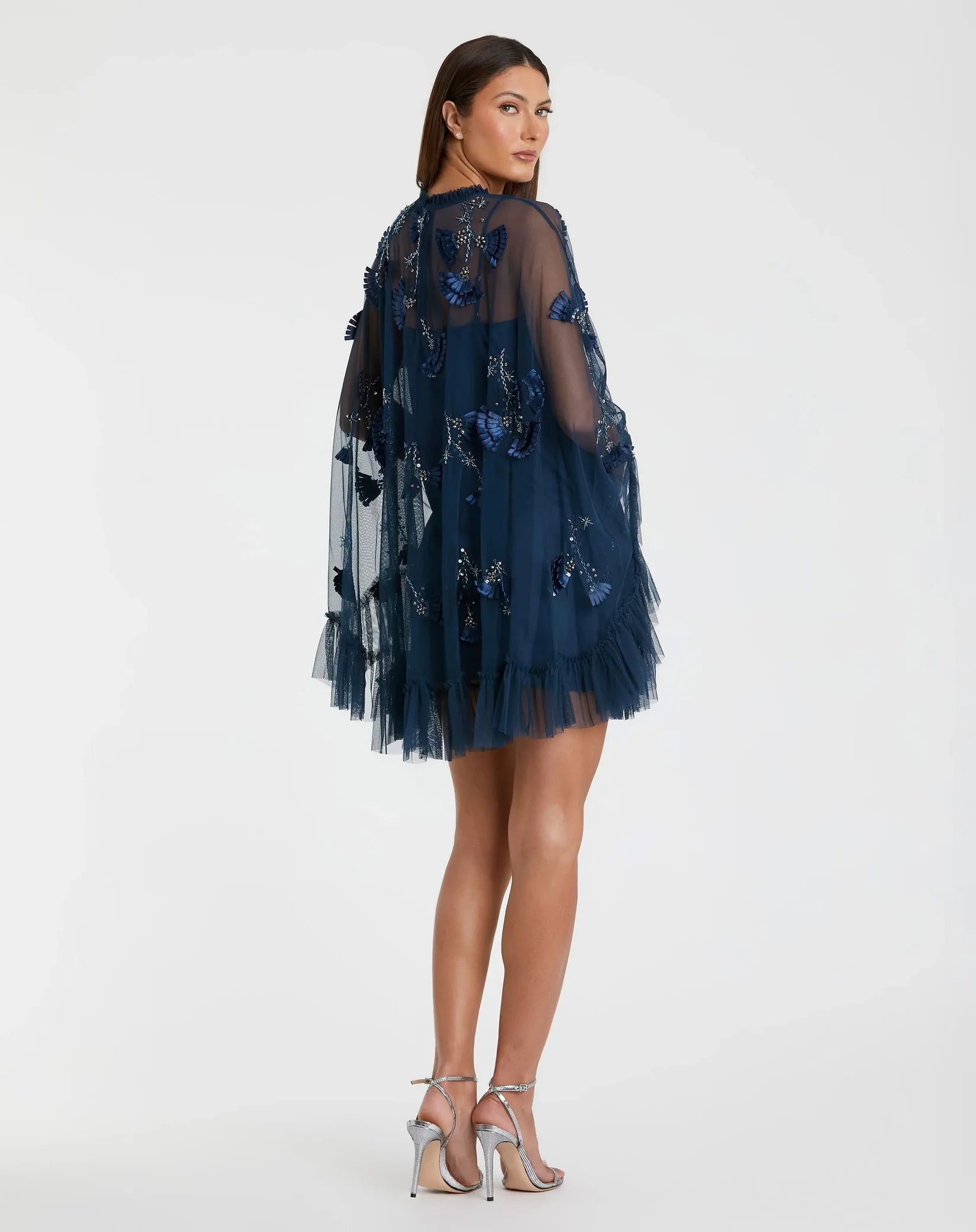 Woman wearing a navy blue dress with floral embroidery on a white background