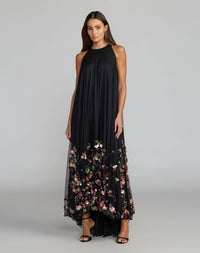 Model wearing Mac Duggal 94270 black floral sequin trapeze gown in a garden setting