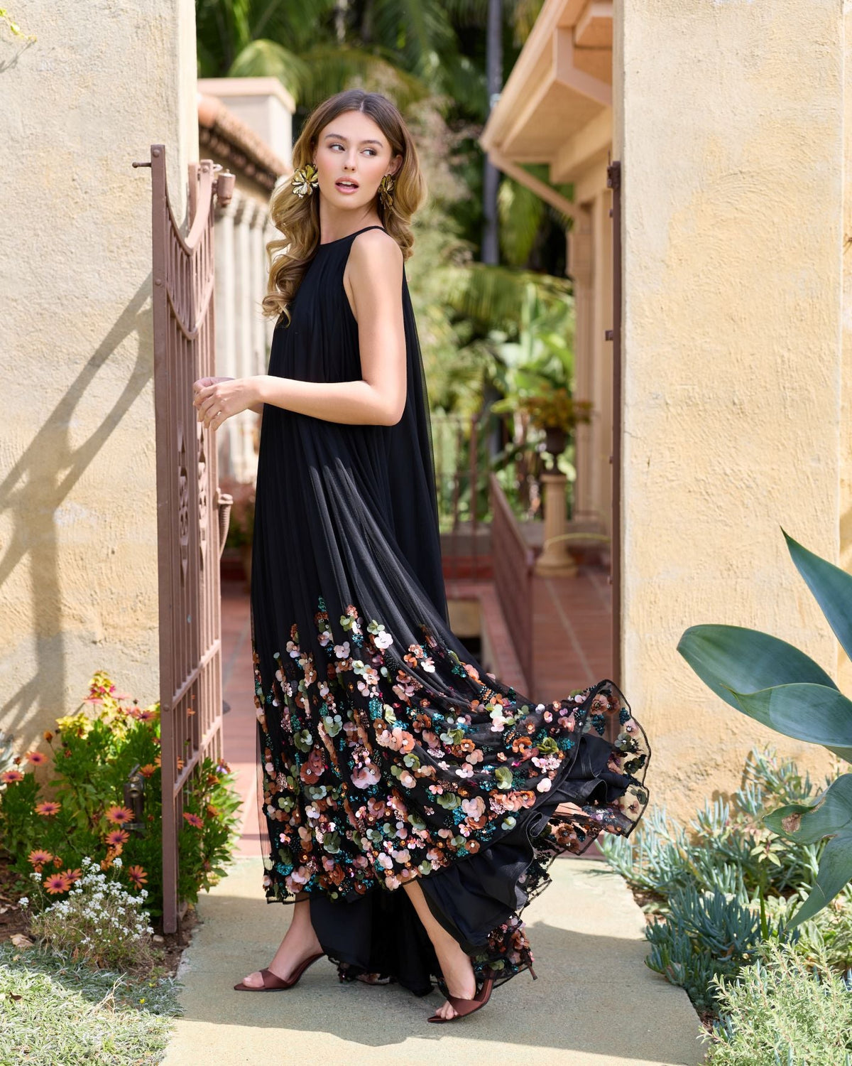 Side view of model in sleeveless black high neck gown