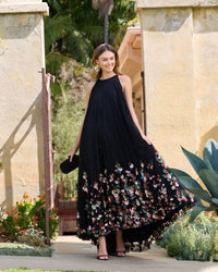 Model smiling in black sleeveless floral gown