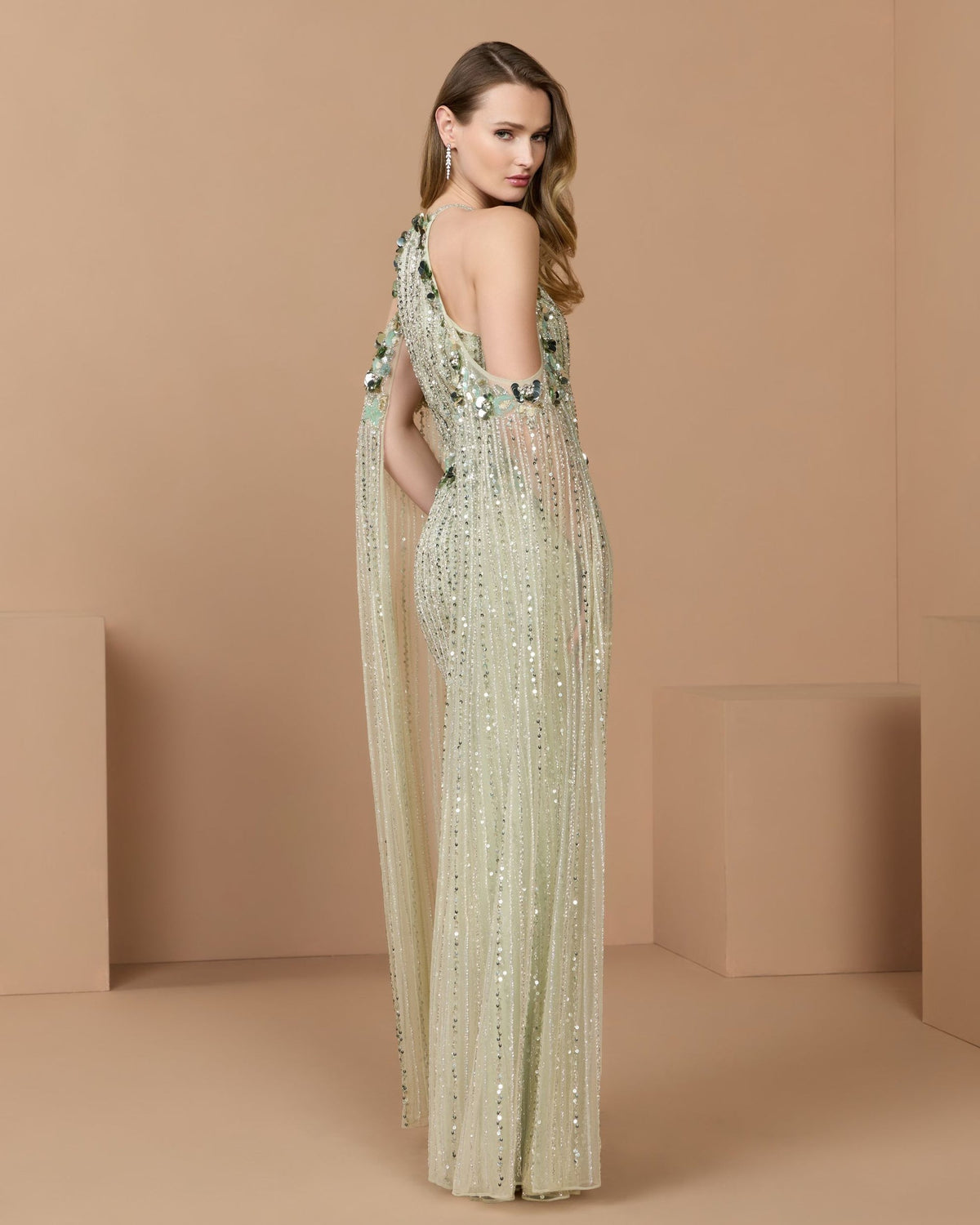 Side-back view of the seafoam gown, showcasing the intricate beadwork and flow of the cape sleeves.