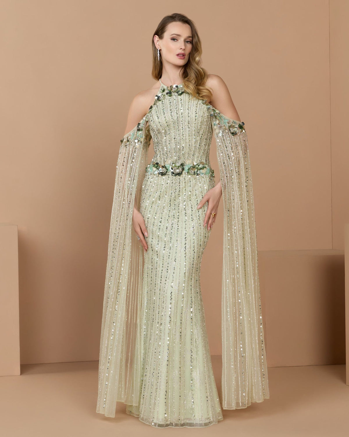 Full-length front studio view of the seafoam embellished mesh column gown with draped cape sleeves.