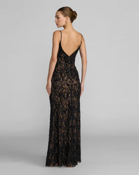 A woman modeling a floor-length black lace evening gown from the back, featuring thin spaghetti straps, a deep V-back, and a fitted silhouette against a light gray studio background.