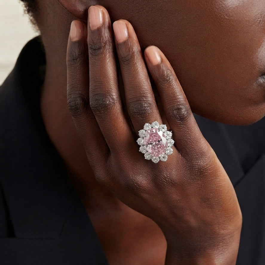 A close-up lifestyle shot of a model wearing a replica of lady gaga's engagement ring which is large pink floral cluster ring on a silver band 