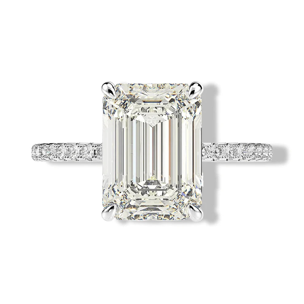 Clean top-down isolated product image of a high-clarity 5 carat emerald cut timeless gemstone promise and cocktail ring on a pavé sterling silver setting.