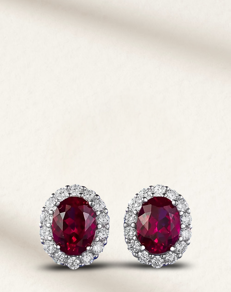 Ruby and diamond halo stud earrings in gold, featuring round-cut ruby centers surrounded by pavé diamonds