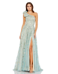 This incredible sage green gown is made from shimmery, botanical-embroidered tulle with with a rhinestone trim at the waist and topped with a feminine full bow at the single shoulder. It’s glamorous, romantic—and with a high leg slit—flirty, too. This gown is perfect for wedding guests and Summer parties!