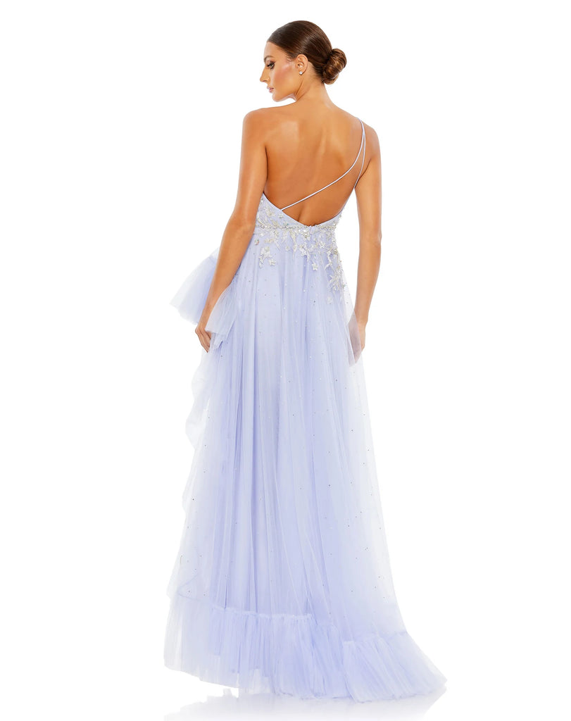 Made in a pretty shade of periwinkle blue in tulle with a lining to match, the unique gown is styled with a one-shoulder topline, botanical embroidery, glittering rhinestone accents, and ruffle trim. The dress trades a more traditional slit for a dramatic asymmetrical cut that highlights lots of leg back view