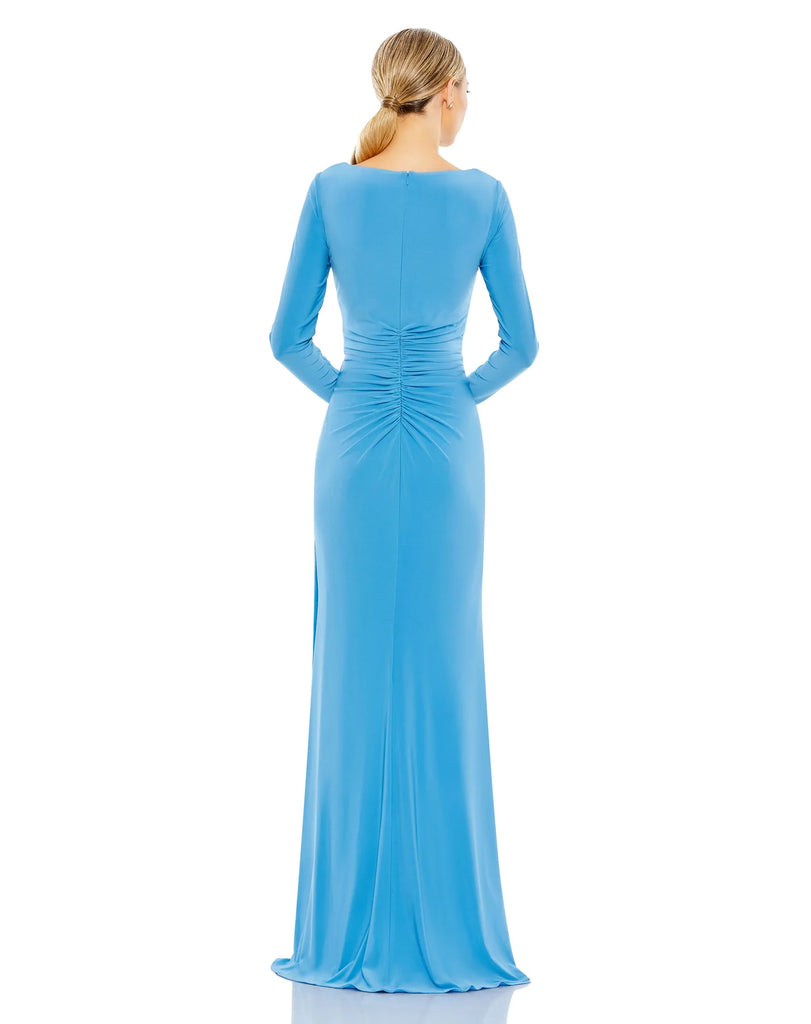 This elegant Duggal jersey, bodycon, turquoise evening dress is sophisticated in every way. With long sleeves and a floor-length skirt together with faux wrap detail at the waist and one sexy thigh high split. This gorgeous aqua gown is perfect for proms, black-tie affairs, weddings and special events back view