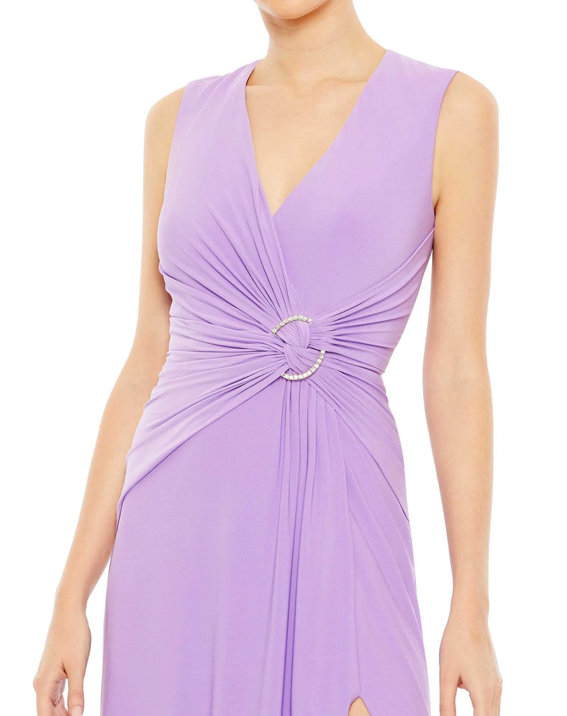 This elegant Mac Duggal floor-length, lilac, short sleeve, evening dress is a beautiful, long, simple and sleek, jersey gown with gathering at the waist finished with a rhinestone buckle and a sexy leg slit to create easy and simple movement. This gown is perfect for proms, black-tie affairs, weddings, brides and special events close up